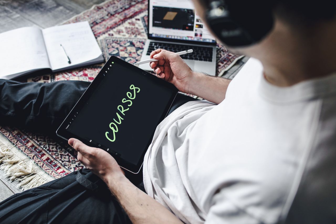 About Person studying online courses using a digital tablet while relaxing indoors with headphones.