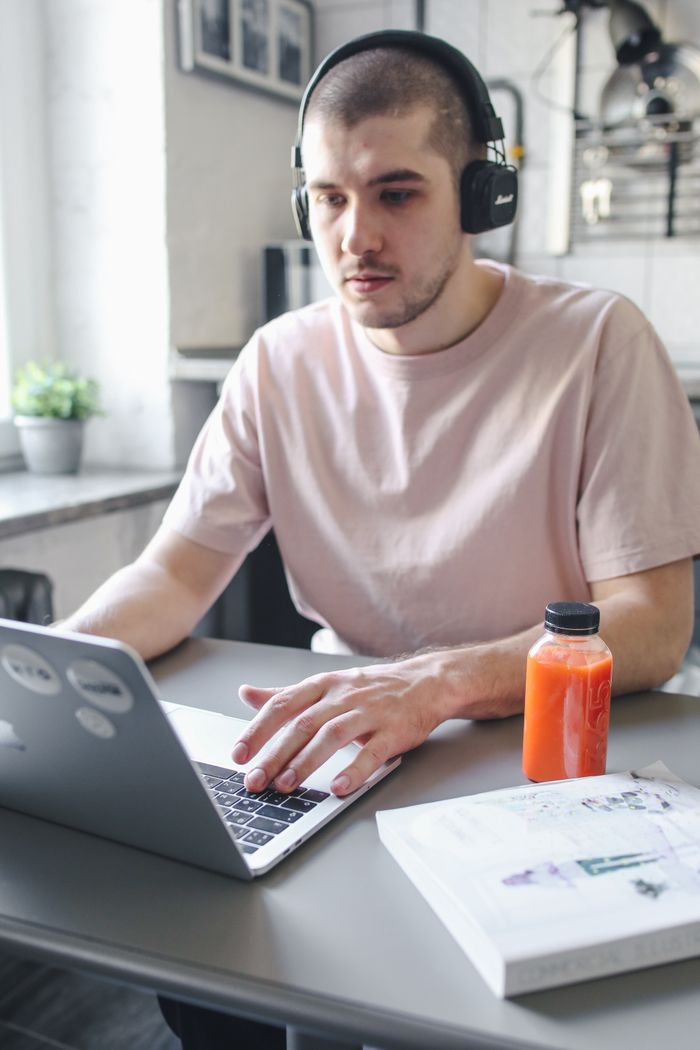 The Art of Drawing Readers In: Your attractive post title goes here Young man working on laptop with headphones, focused on remote tasks indoors.